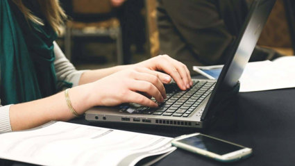 Close up of a person's hands typing on a laptop.