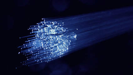 A bundle of optical fibres white which look like a ray of blue light on dark room.