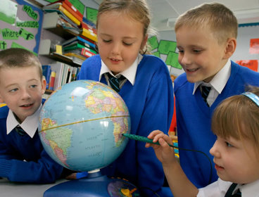 Four primary school children viewing a globe.