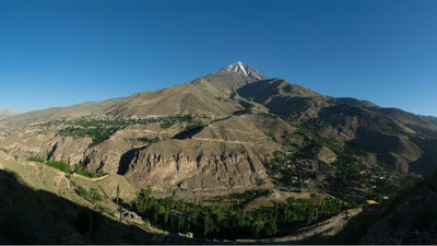 A wide-lens angle view of a mountain with a small town below.