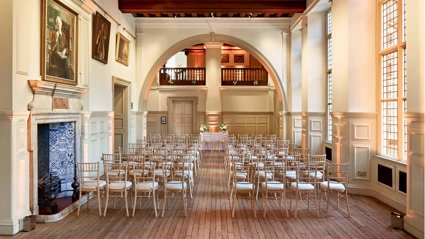 Wooden chairs setup for a wedding ceremony underneath the arch in the Main Hall.