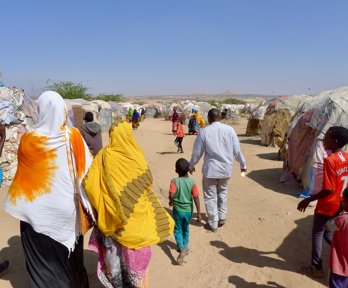 A group of people walkng through a tented settlement