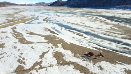 Streams of meandering glacial meltwater between areas of bare rock in the base of a valley. 