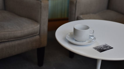 A coffee table with a cup and saucer and a card that says Royal Geographical Society.