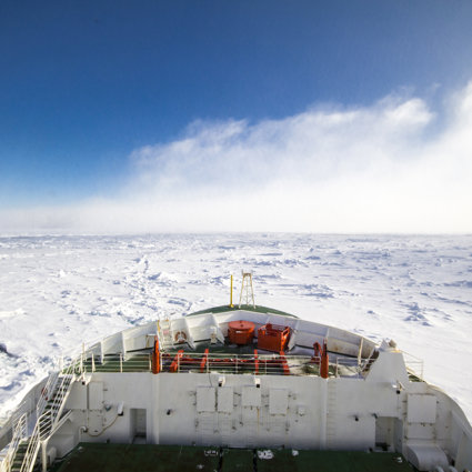 Looking out to the front of the SA Agulhas II ship sailing through the ocean in Antarctica, with pack ice all around