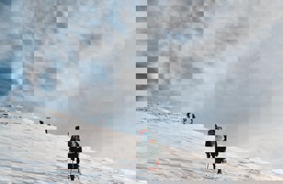 A group of people walk up a snowy steep mountain